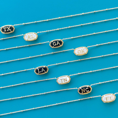 kendra scott necklaces laid out in front of a blue background