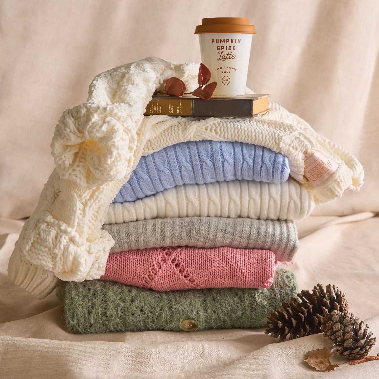 a folded stack of sweaters with a fall theme