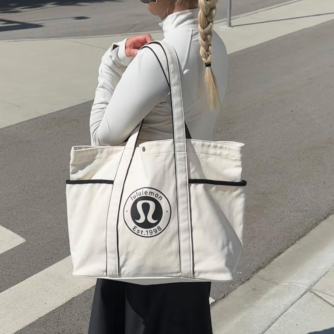Lululemon with bag A girl carrying a white Lululemon tote bag.